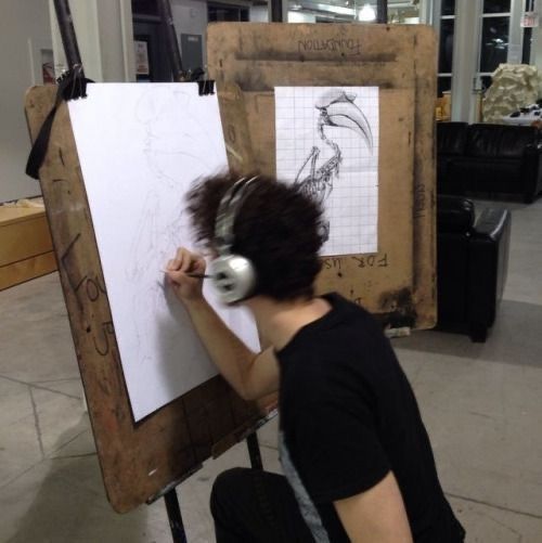 a man sitting in front of a white board with headphones on and writing on it