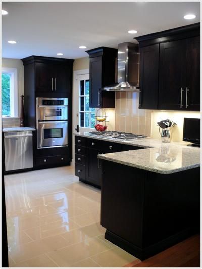 a kitchen with black cabinets and marble counter tops, stainless steel appliances and an island in the middle