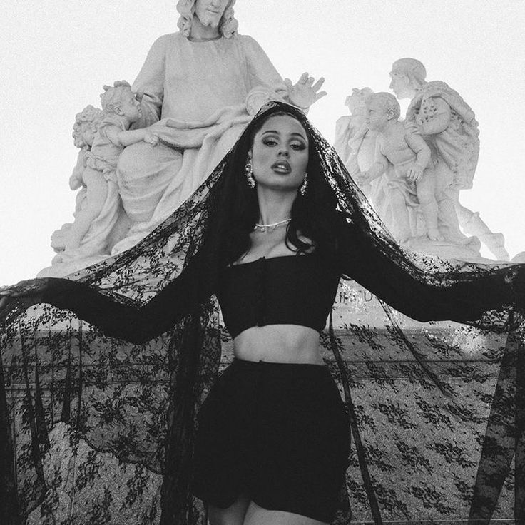 black and white photograph of a woman in front of a statue with her hands on her hips