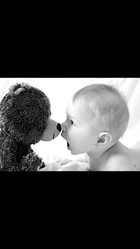 a baby kissing a stuffed animal on the nose