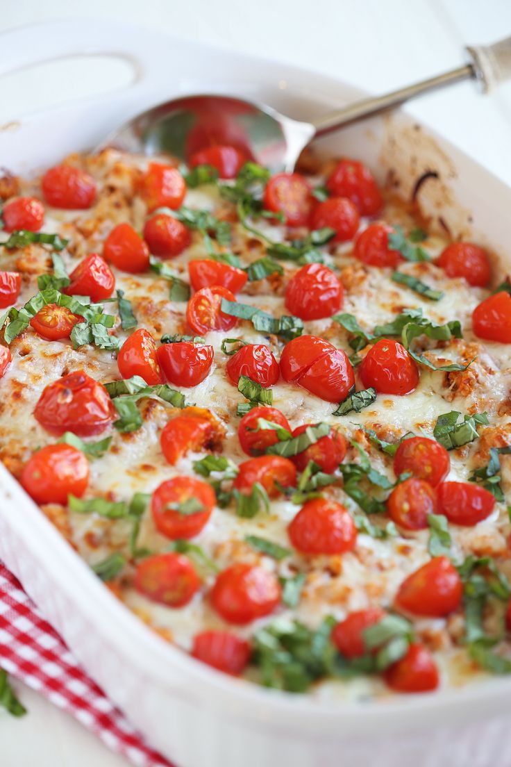 a casserole dish with tomatoes and basil on top, ready to be eaten