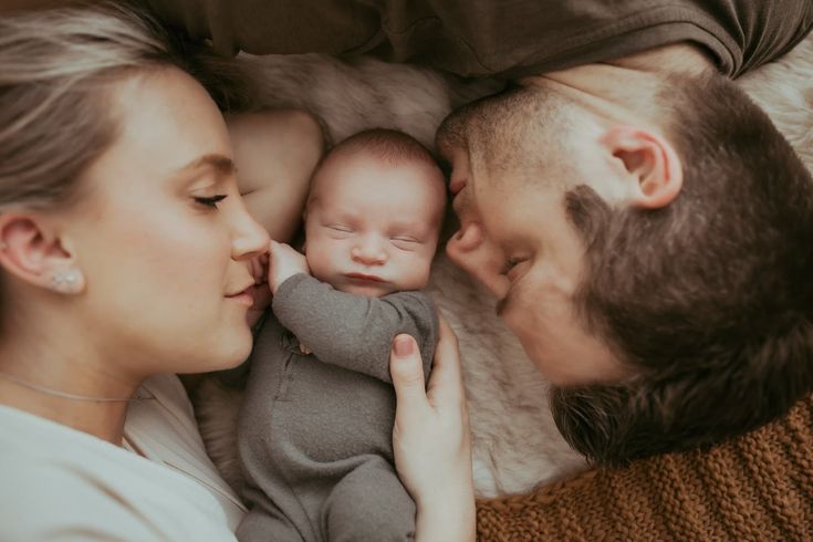 a man and woman laying next to each other holding a baby