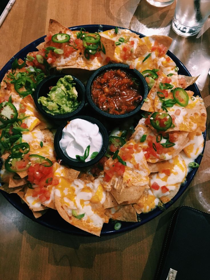 a platter with nachos, salsa and guacamole on it