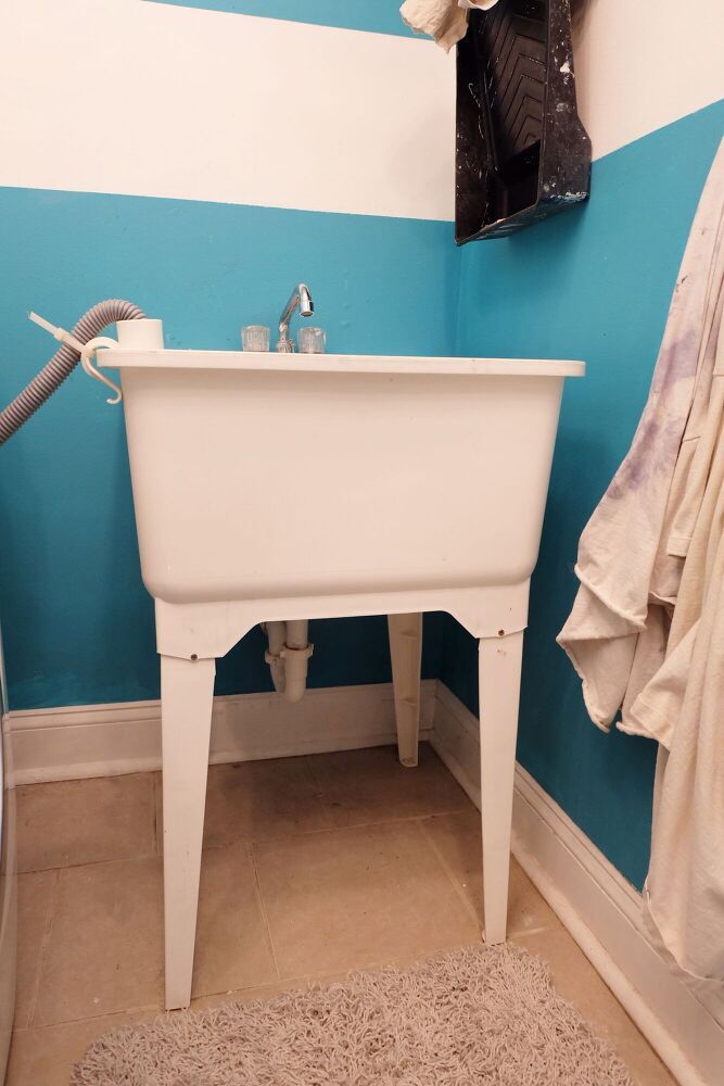 a white sink sitting under a mirror next to a blue and white striped wall in a bathroom