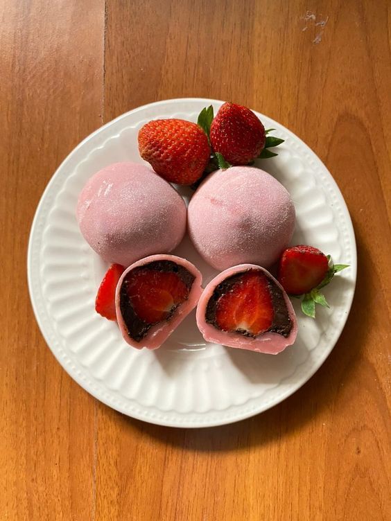 three strawberry ice creams on a white plate with strawberries