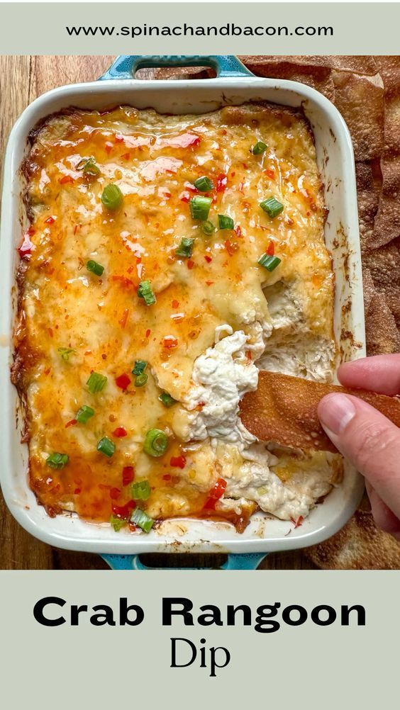 a hand dipping some food into a casserole dish with the title crab rangoon dip