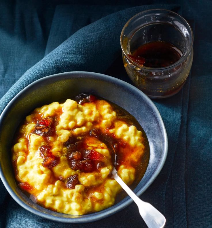 a bowl filled with food next to a jar of syrup on top of a blue cloth