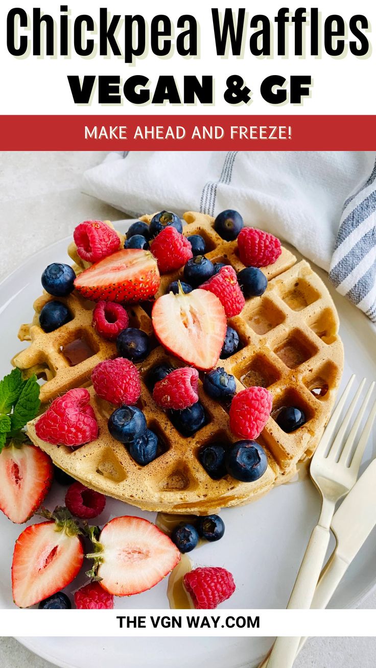 a white plate topped with waffles covered in berries and blueberries next to a fork