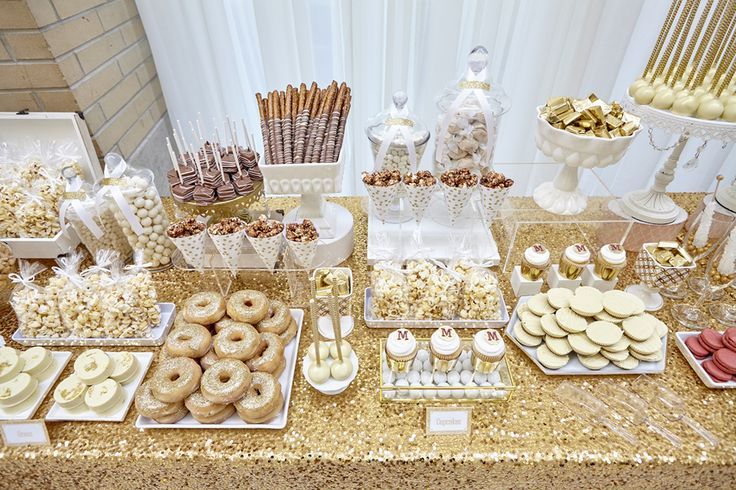 a table filled with lots of desserts and sweets on top of gold sequin covered tables