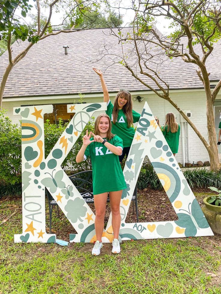 two girls posing in front of the letters k and k are painted green, yellow and white