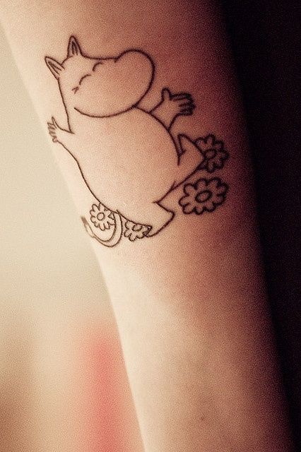 a small tattoo on the arm of a person with a cat and flowers around it