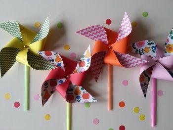 three colorful pinwheels sitting on top of a white table next to polka dots