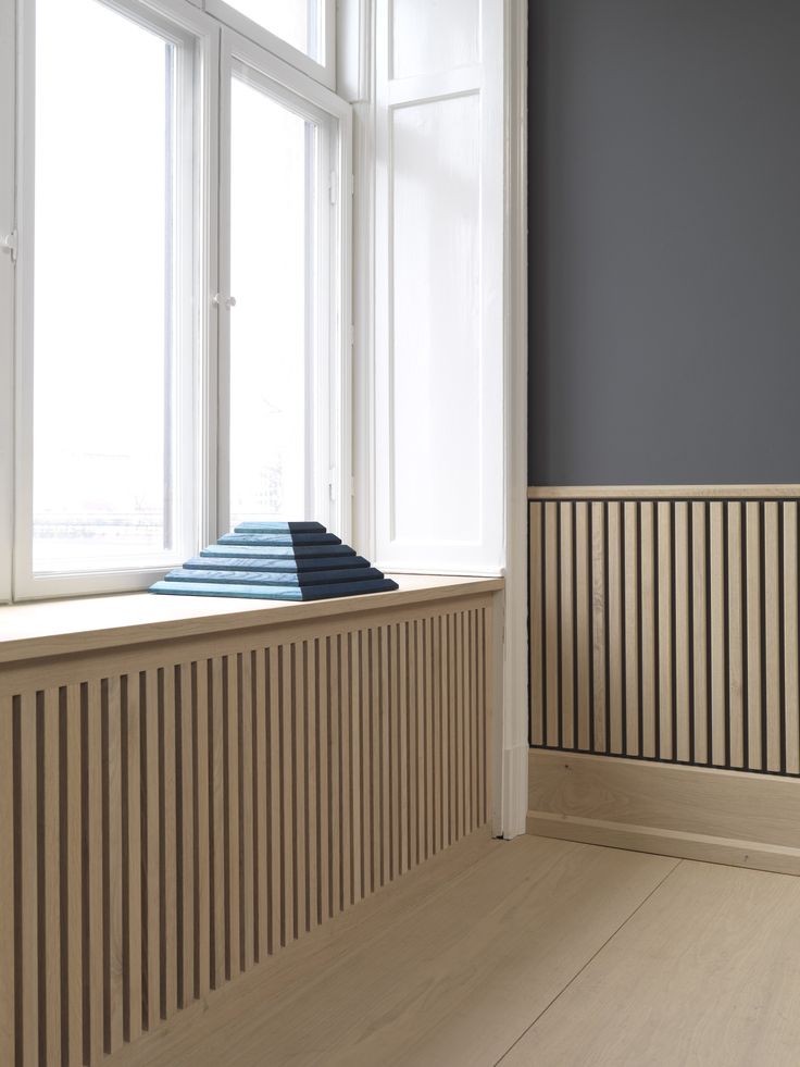 an empty room with wooden slats on the wall, and blue rugs in the window