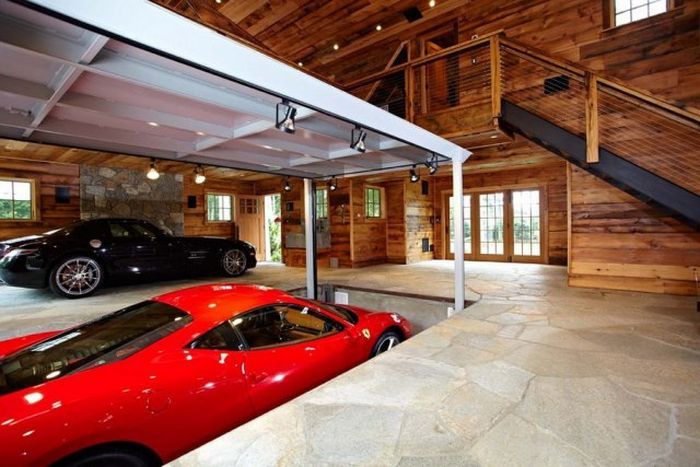 two red sports cars parked in a large garage with stairs leading up to the second floor