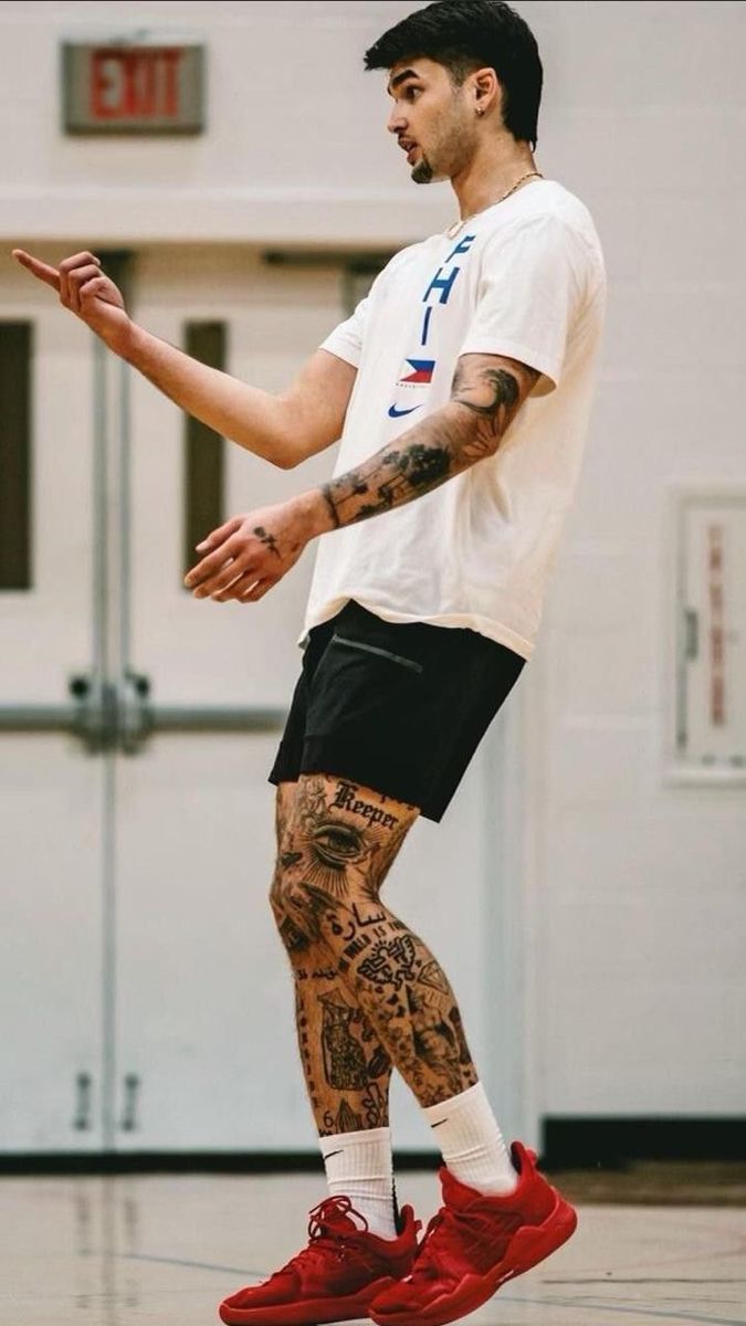 a man with tattoos on his legs playing basketball