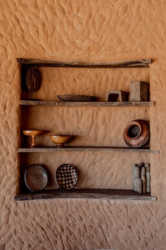 a shelf with bowls and other items on it in a room that looks like an adobe house