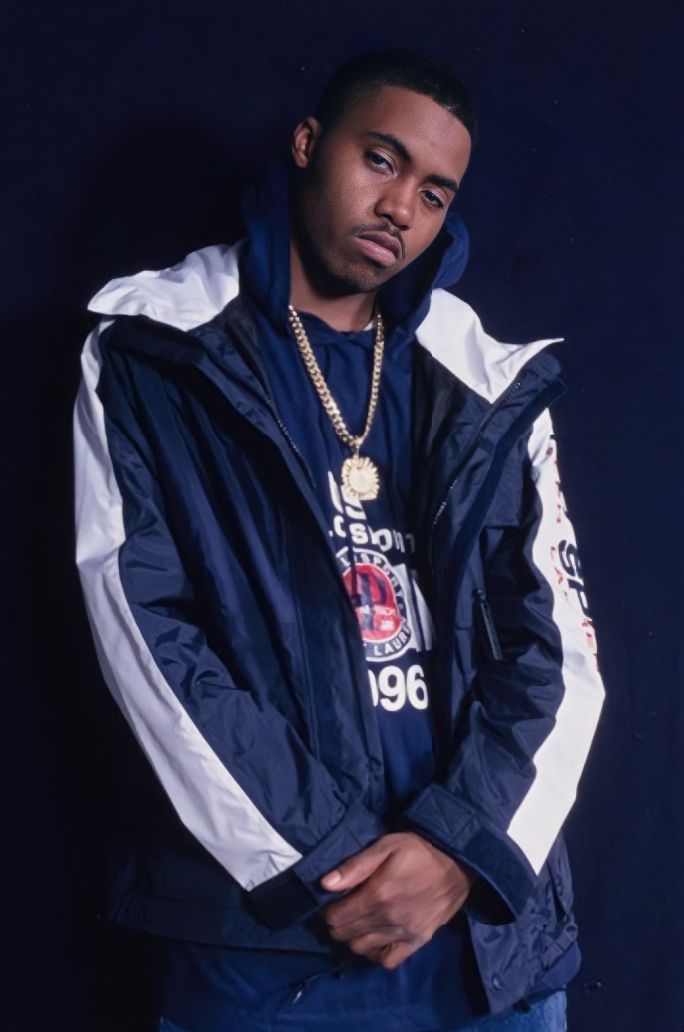 a man wearing a blue jacket and white shirt standing in front of a black background