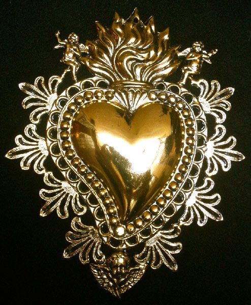 a gold heart shaped brooch sitting on top of a black surface with filigrees