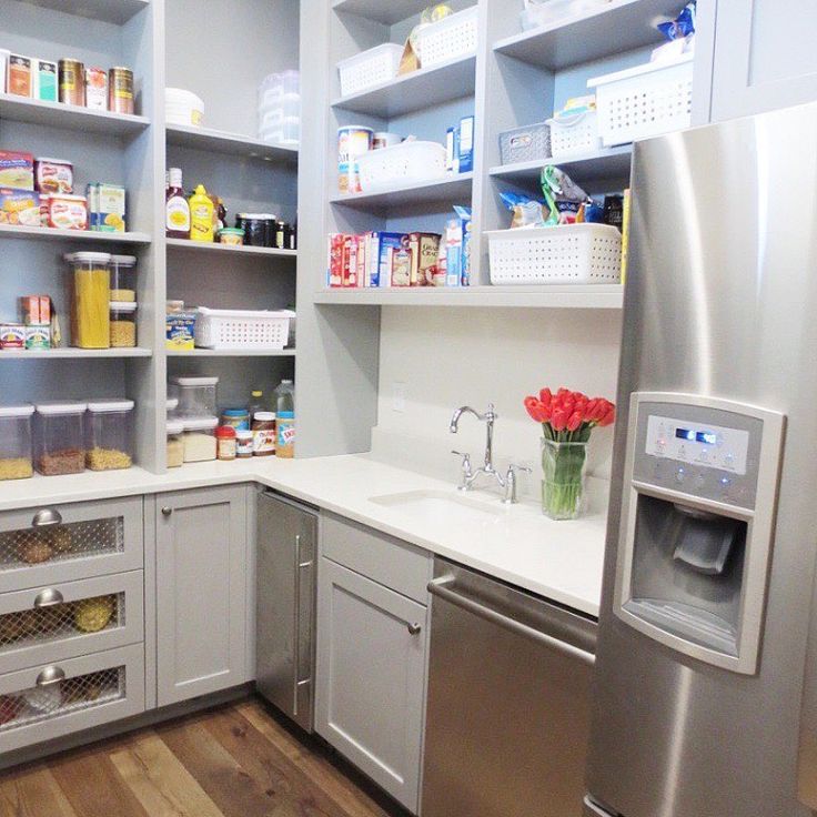 a kitchen with stainless steel appliances and white cupboards filled with food, drinks and condiments