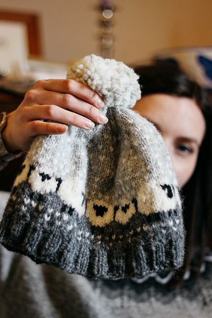 a woman is holding up a knitted hat