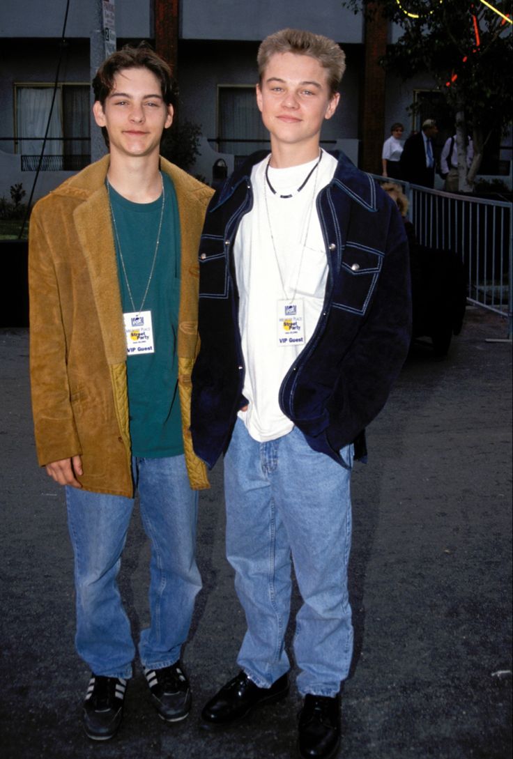 two young men standing next to each other in front of a building at an event