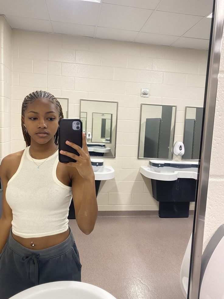 a woman taking a selfie in a bathroom mirror with her cell phone up to her ear