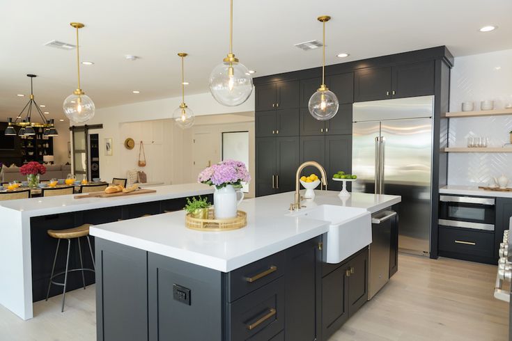 a large kitchen with an island in the middle and two pendant lights hanging from the ceiling