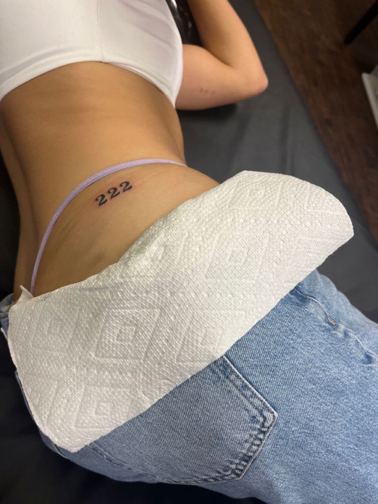 a woman's stomach with the number 532 tattooed on her lower back and side