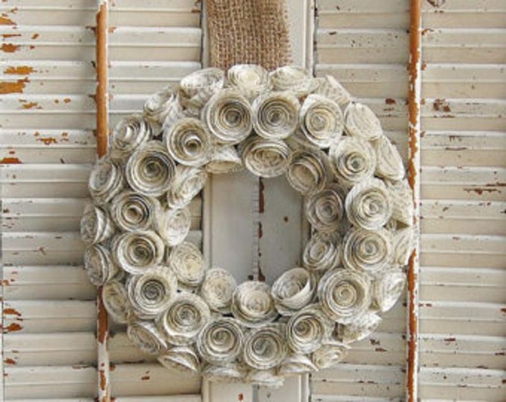 a white wreath hanging on the side of a building next to a wall with peeling paint