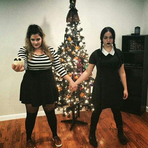 two young women holding hands in front of a christmas tree