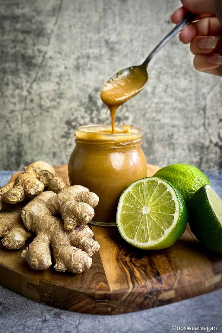 a person is spooning honey into a jar filled with ginger and lime