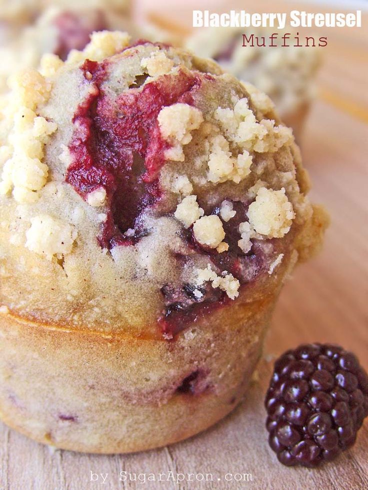 muffins with crumbs and blackberries on a wooden surface