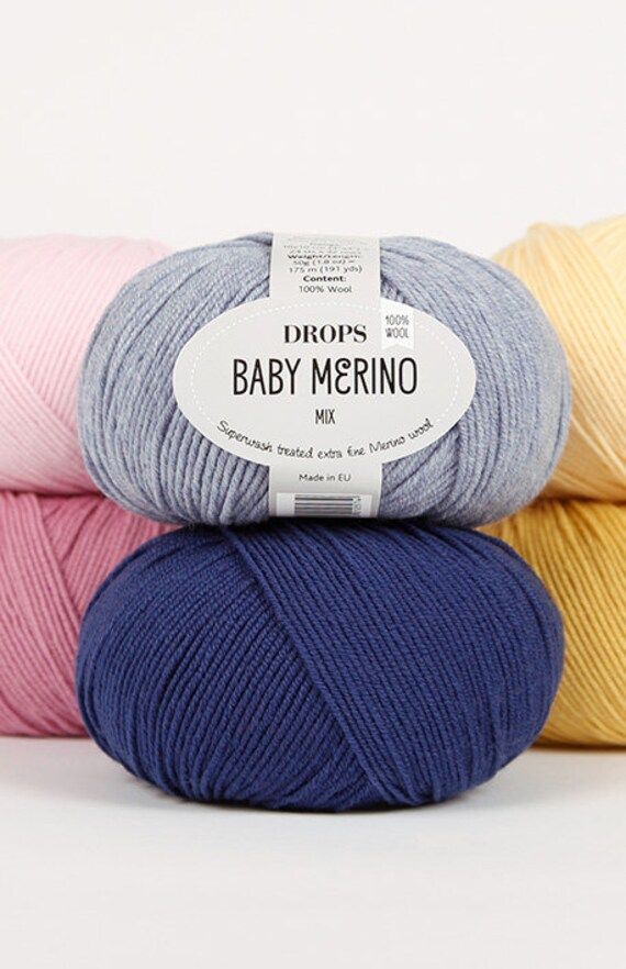 three skeins of baby merino yarn in various colors and sizes on a white background