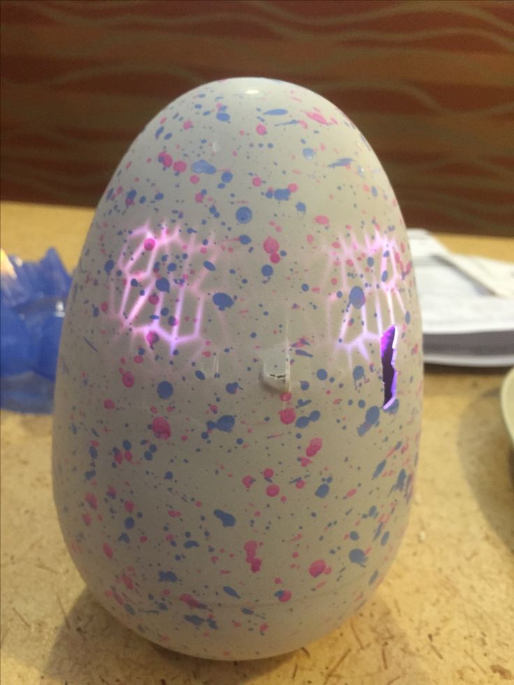 an egg that has been painted with pink and blue splatters on it, sitting on a table