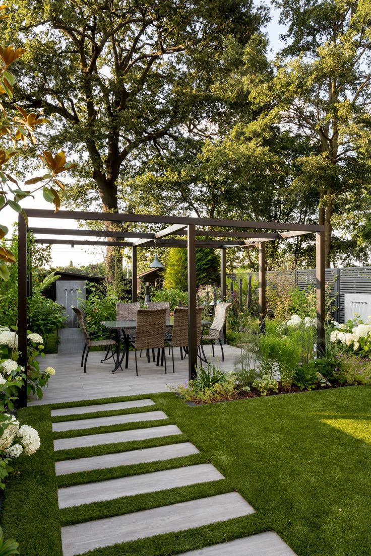 a garden with grass and stepping steps leading up to the pergolated patio area