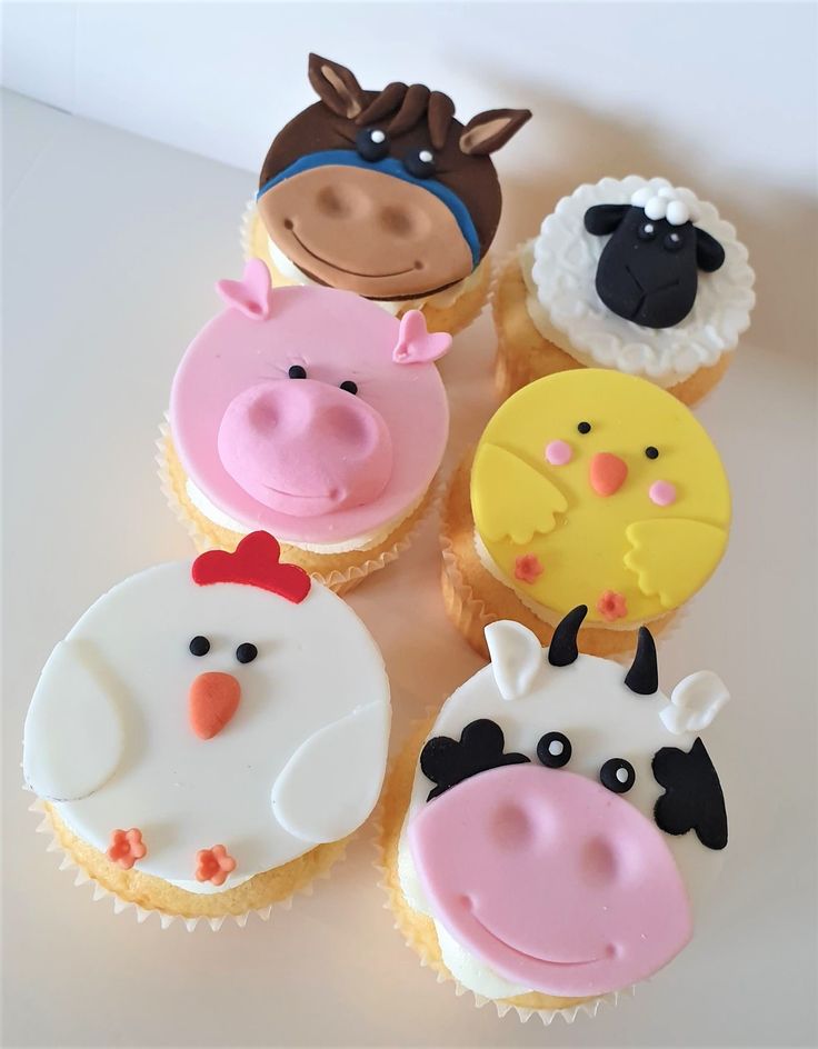 cupcakes decorated with farm animals are on a table