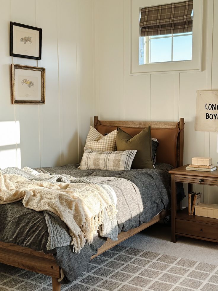 a bed sitting in a bedroom next to a wooden table with a lamp on it