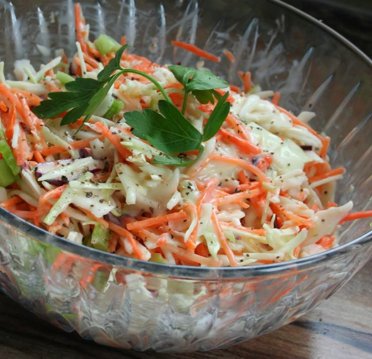 a glass bowl filled with coleslaw and carrots