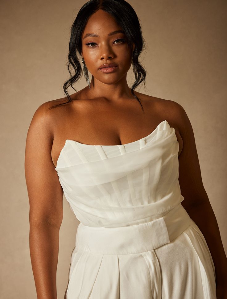 a woman in a white dress posing for the camera with her hands on her hips