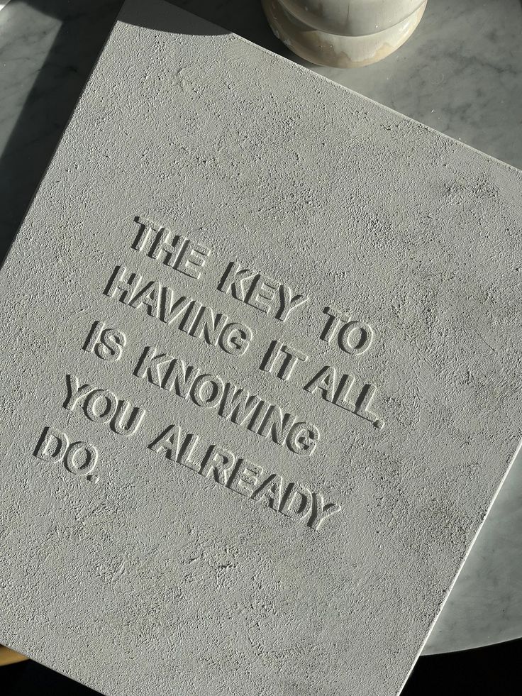 the words are etched into the stone on the table top, which is surrounded by white vases