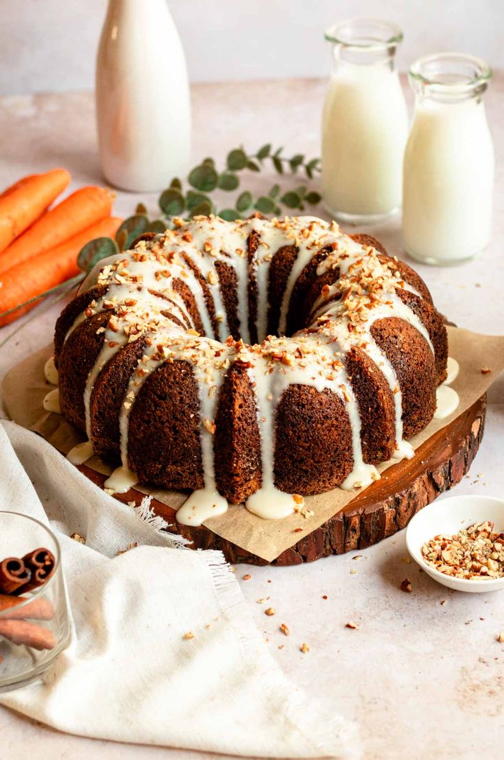 a bundt cake sitting on top of a wooden cutting board next to carrots