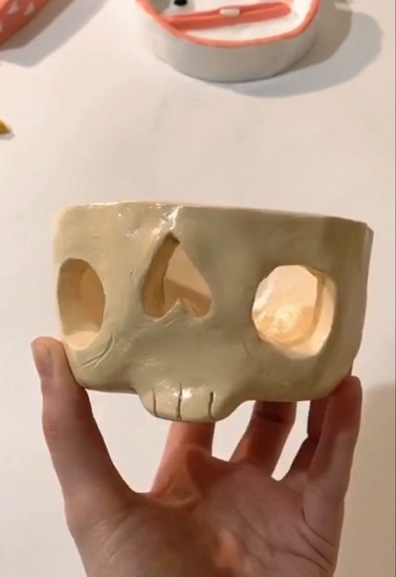 a person holding up a fake skull with holes in it