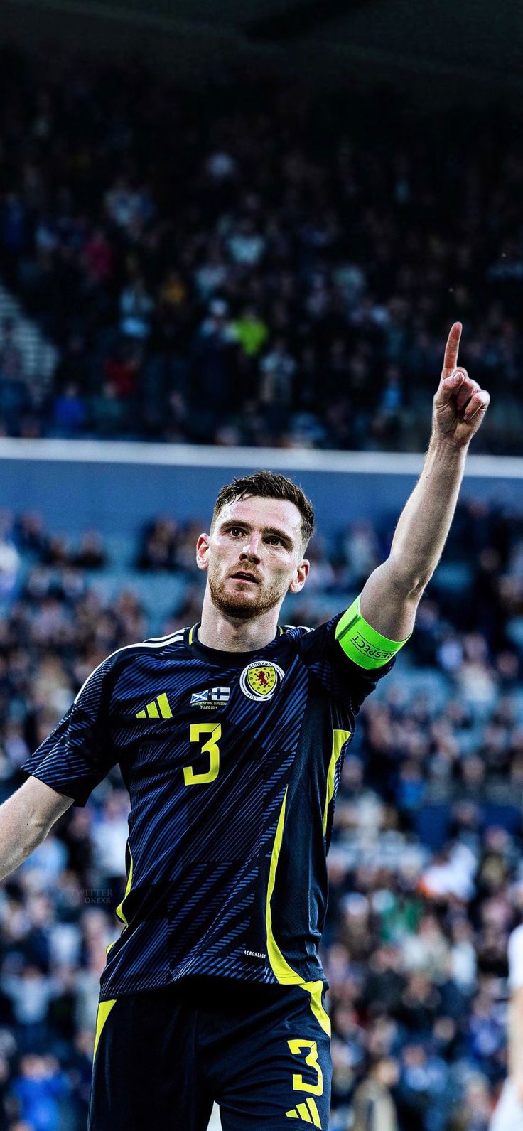 a male soccer player is holding his hand up in the air and looking at the crowd