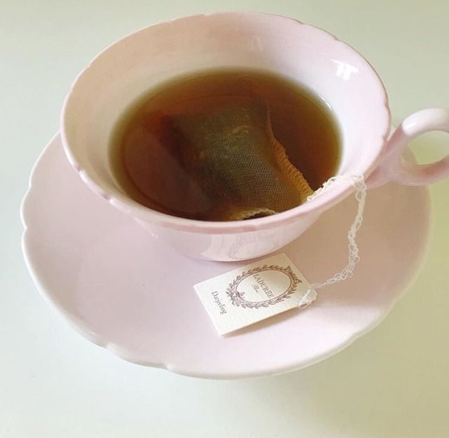 a tea bag in a pink cup on top of a saucer with a white tag