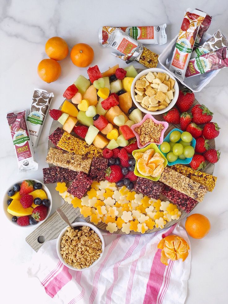 a platter filled with fruit, nuts and crackers on top of a table