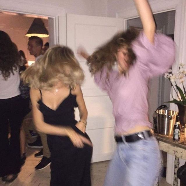 two women are dancing in a room with other people