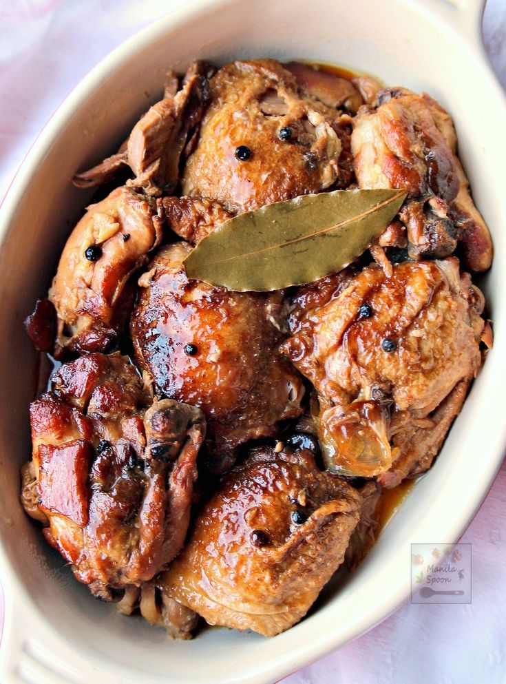 a bowl filled with meat covered in sauce and topped with a green leaf on top