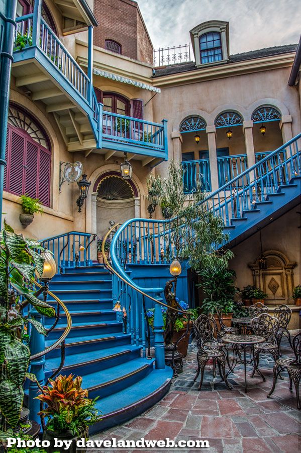 the blue stairs lead up to an outdoor dining area with tables, chairs and potted plants