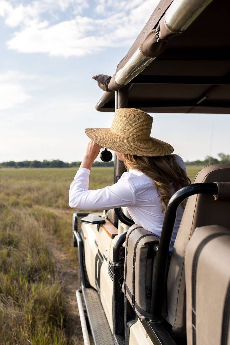 a woman sitting in the back of a truck with a hat on top of her head