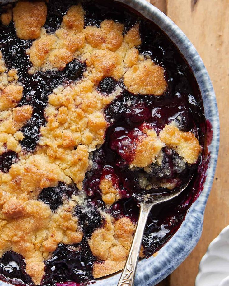 a blueberry cobbler in a bowl with a spoon on the side, ready to be eaten